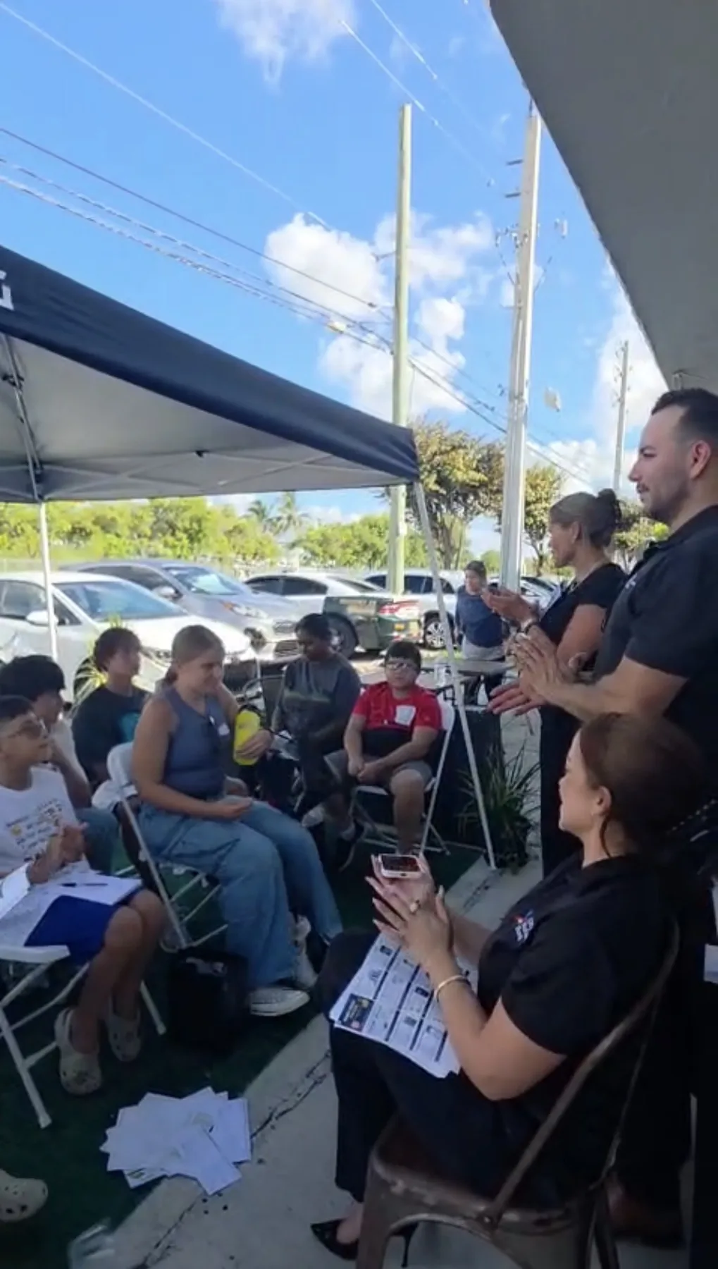 Future Leaders outdoor program with students and families seated under shade.